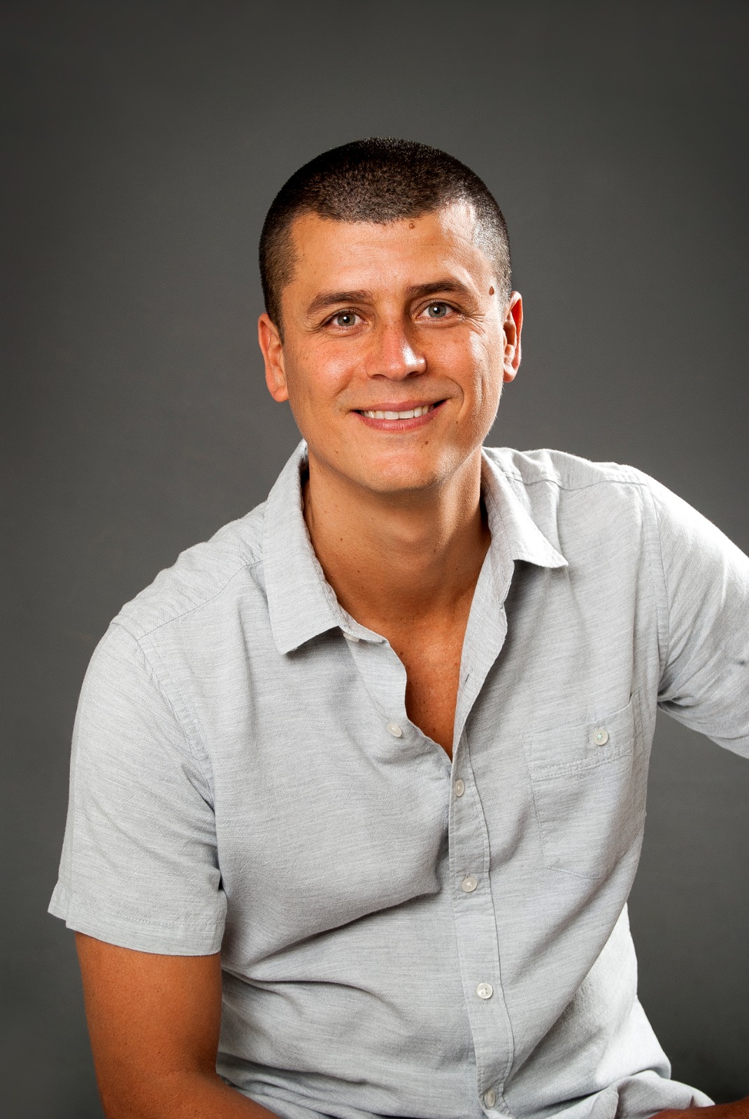 Carlos Picado smiling in a light gray shirt